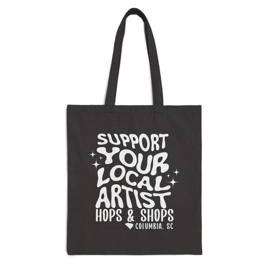 Black tote bag with white text 'Support Your Local Artist Hops & Shops Columbia, SC' on a white background